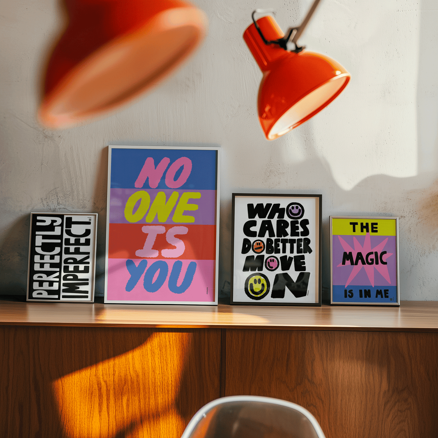 Framed motivational posters on a wooden shelf with orange lamps casting shadows.