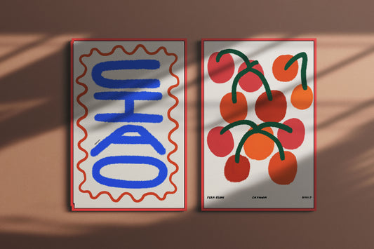 Two posters on a brown surface, one with blue text and red border, the other with red cherries and green stems.