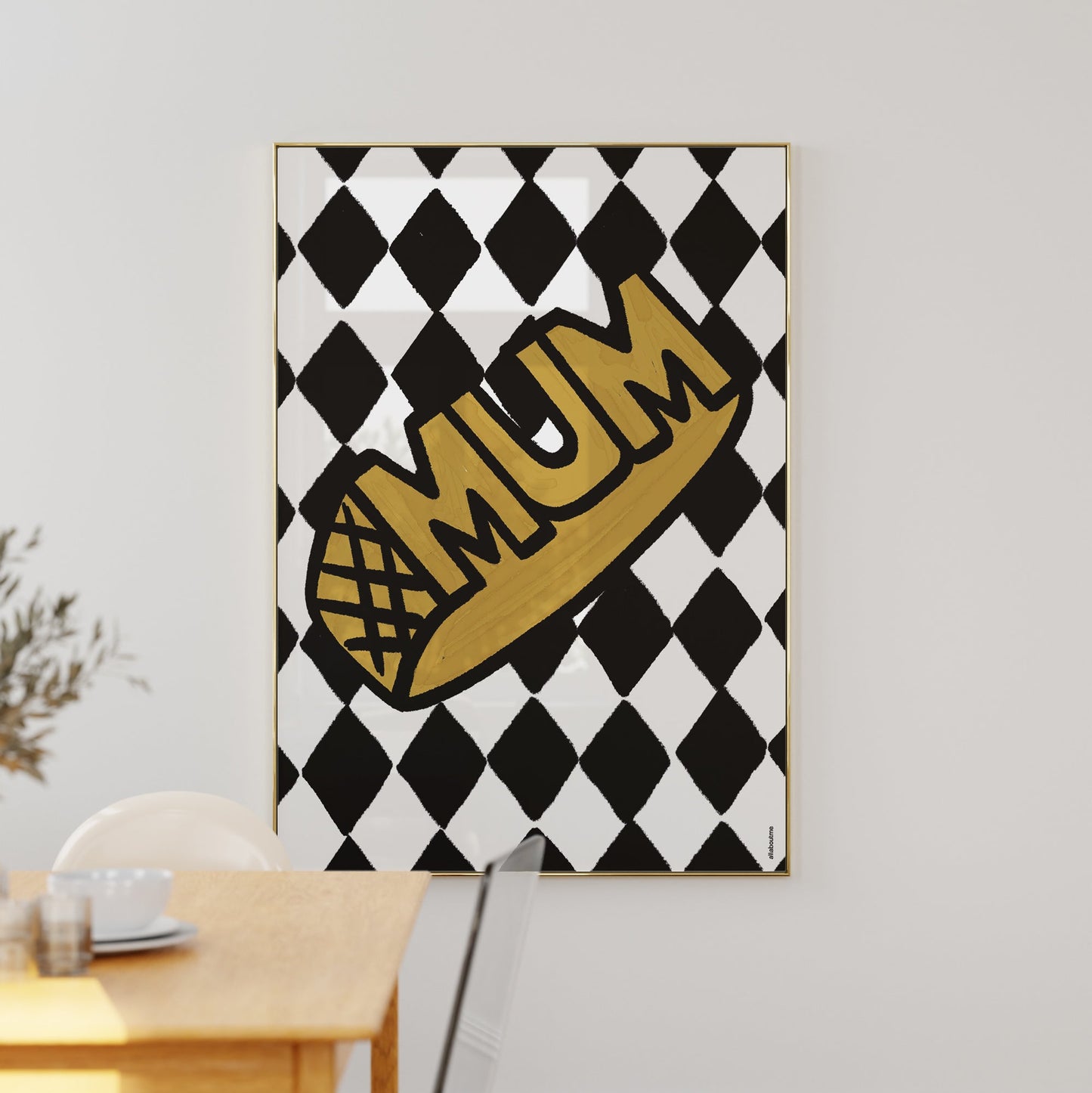 Framed artwork with 'MUM' text on a black and white checkered background, hanging on a wall.