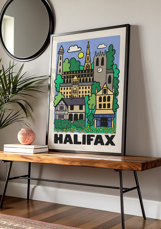 Framed artwork of Halifax West Yorkshire on a wooden bench with a plant and books in the background.