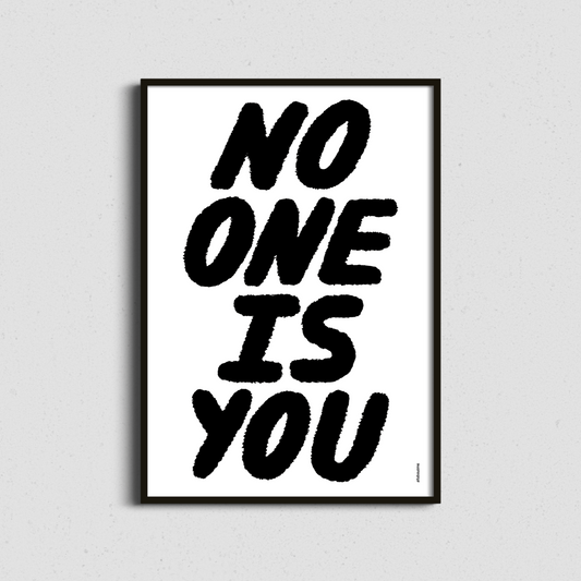 Framed minimalist “No One Is You” print in black and white – modern affirmation art for a clean, stylish space.