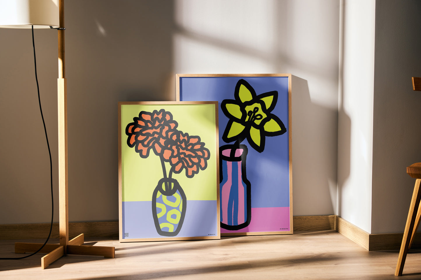 Two colorful birth flower abstract art prints on a wooden surface with a lamp and stool in the background.
