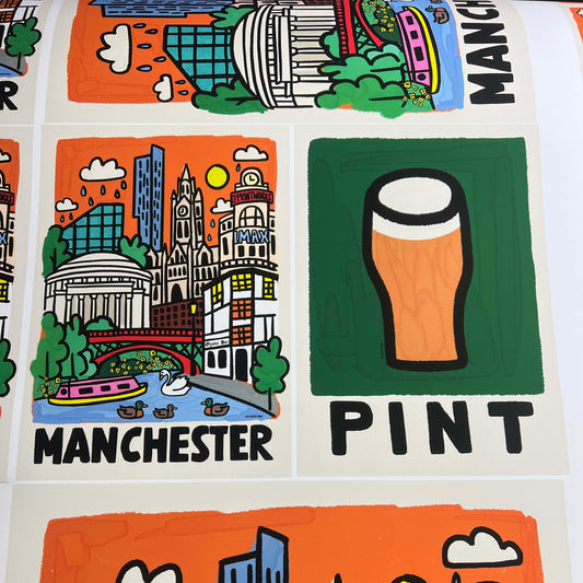 A close-up of a printed Manchester-themed graphic sheet featuring illustrated city landmarks, rain clouds, a yellow sun, and a pint of beer with the word 'PINT' below it.
