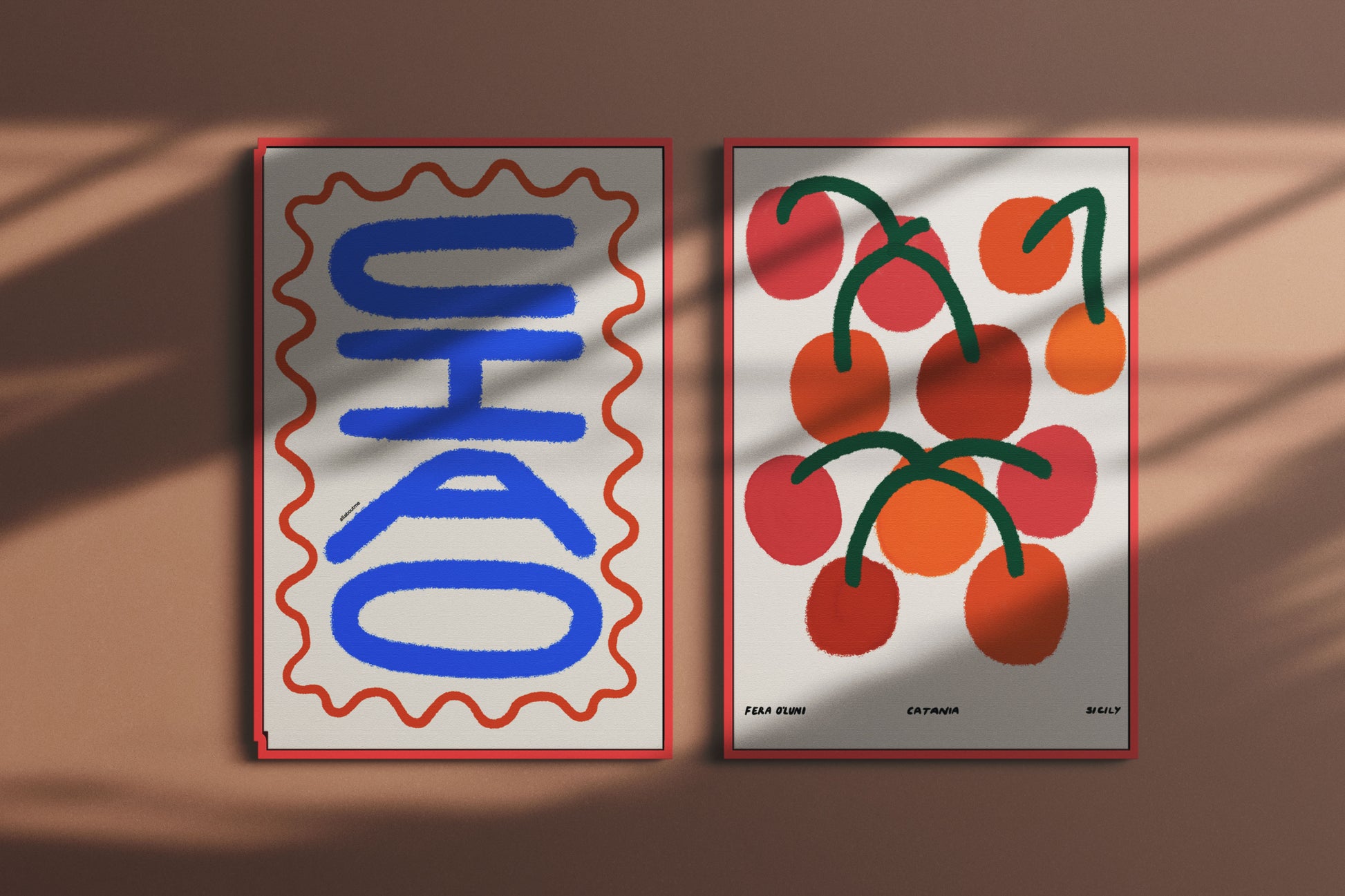 Two posters on a brown surface, one with blue text and red border, the other with red cherries and green stems.