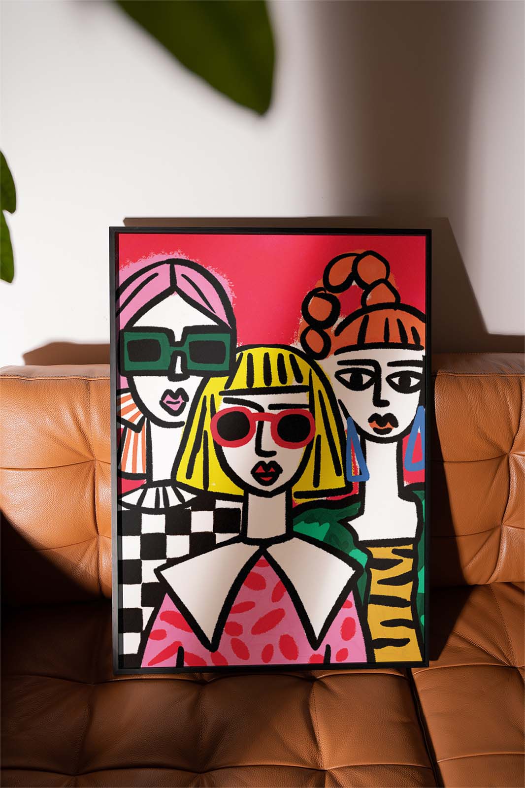 Framed artwork of stylised portraits  Illustration of confident women supporting each other and celebrating friendship.on a brown leather surface