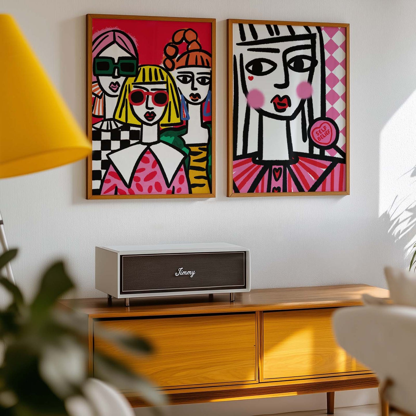 Two colorful abstract paintings on a wall above a wooden cabinet with a Jamo speaker.