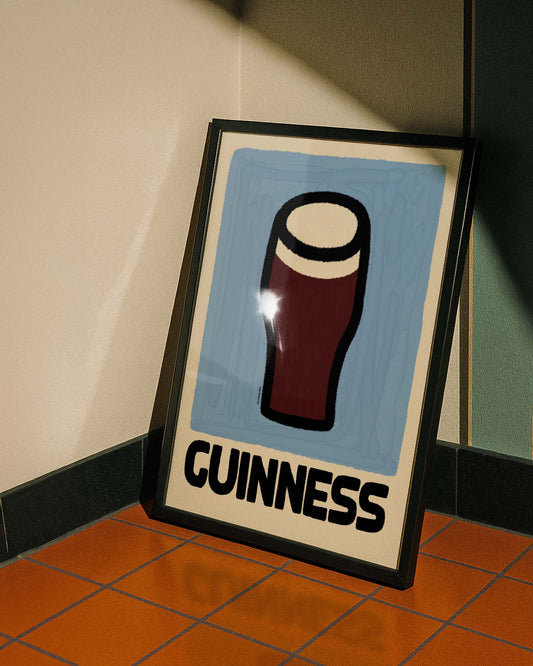 Framed Guinness poster on a tiled floor against a wall.