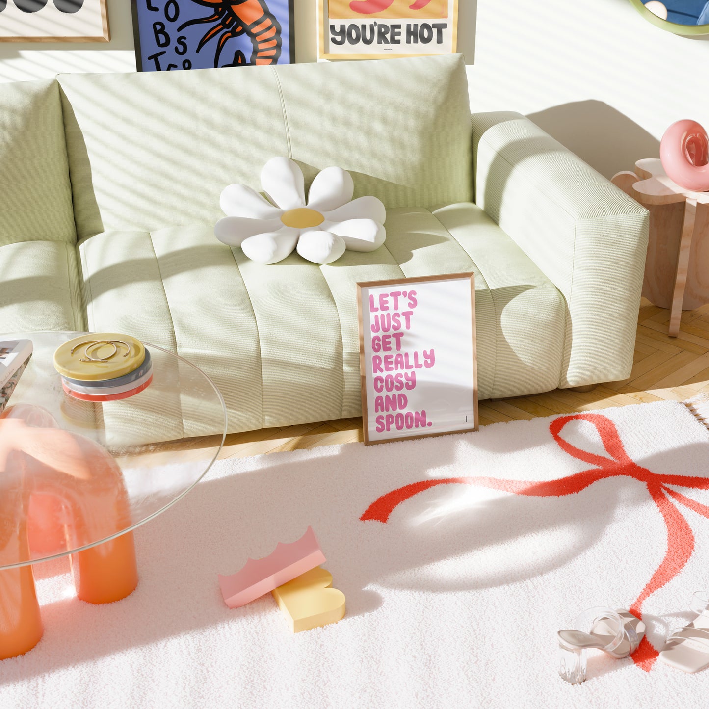 Light green sofa with decorative items including a flower, framed text, and a pink gift on a white surface.