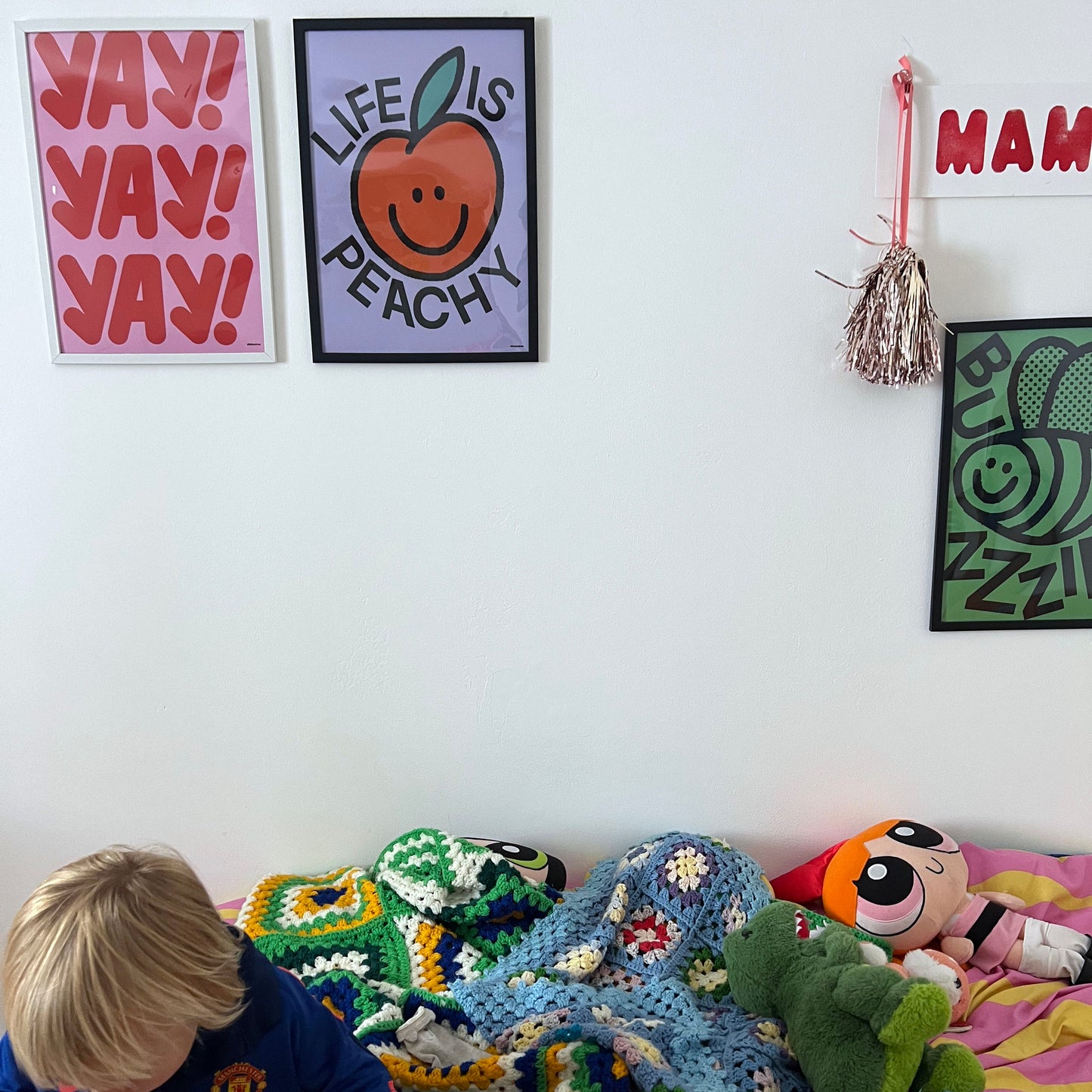 Child playing on a colorful bed with motivational, positive posters on the wall.