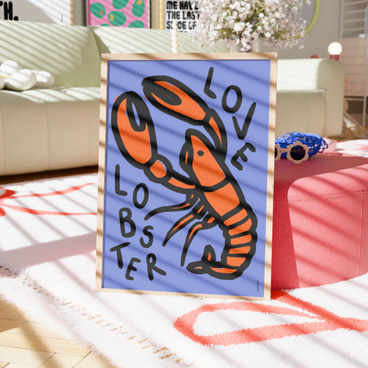 Framed artwork of a lobster with 'LOVE LOBSTER' text on a blue background, placed on a table in a room.