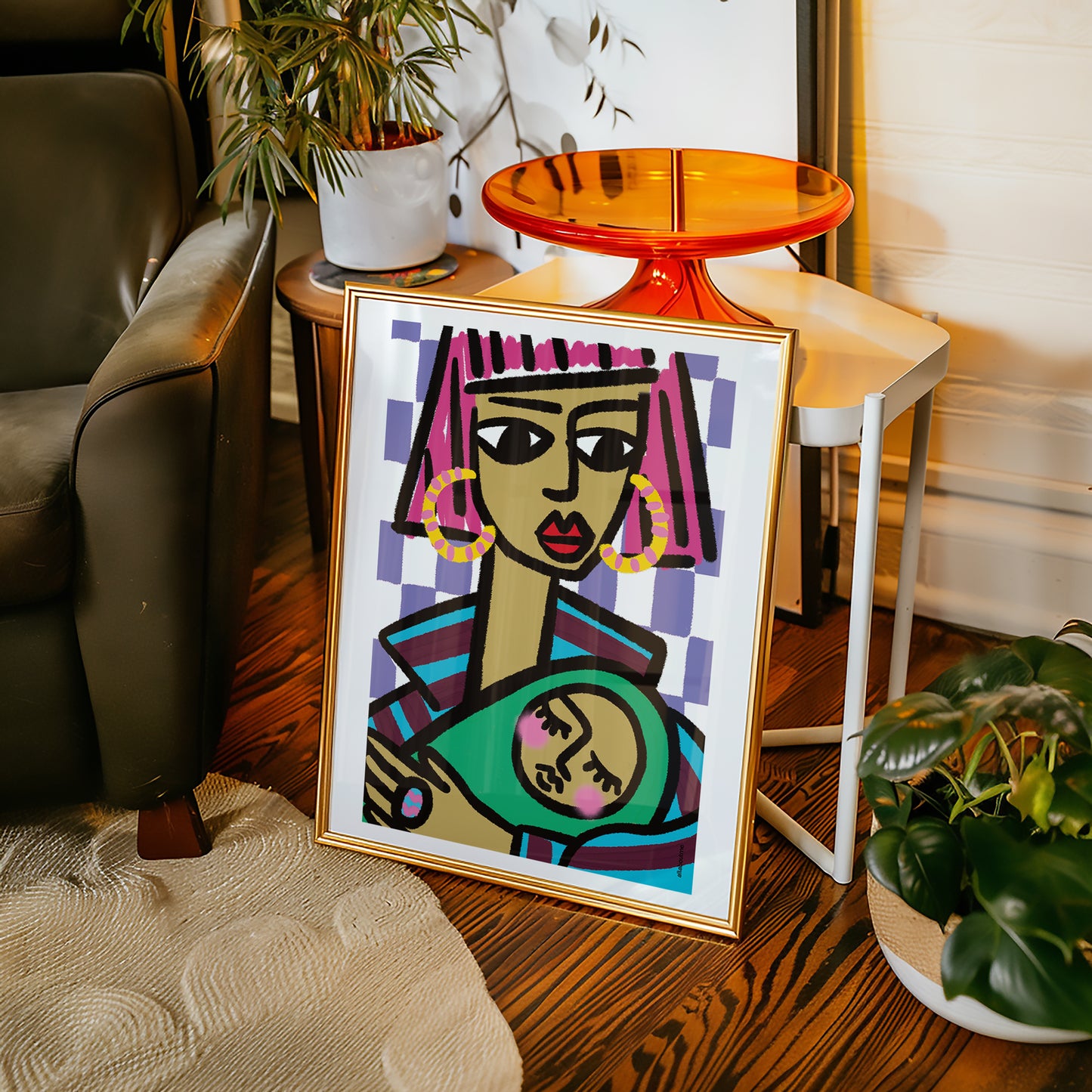 Framed abstract art of a woman with colorful hair and earrings and baby on a wooden floor.