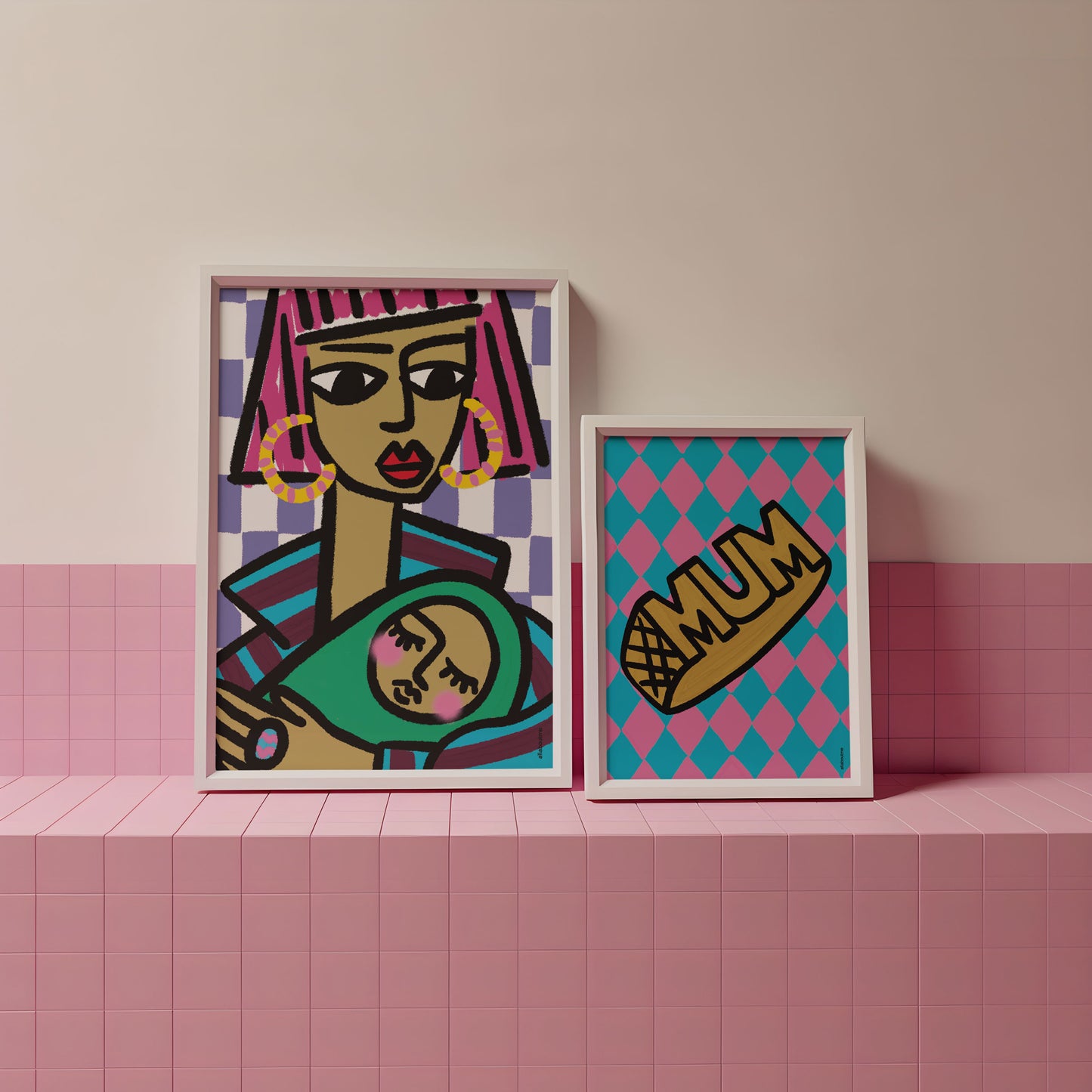 Two framed mum artworks on a pink tiled surface with a neutral wall background