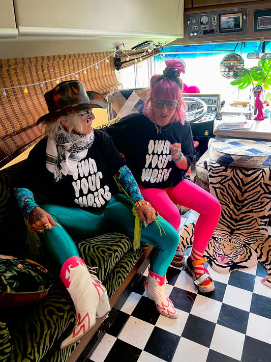 Lu in Luland, AKA Lou Featherstone wearing own your weird tshirt with designer Carla, sitting inside Susie with a checkered floor and colourful interior.