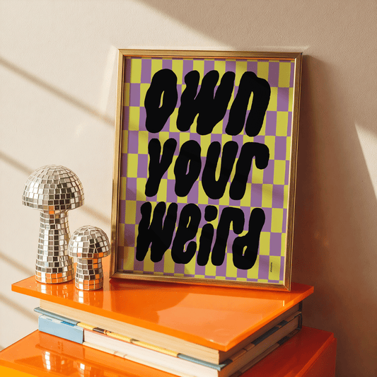  Framed checkerboard art print with bold “Own Your Weird” message – graphic, empowering and stylish.