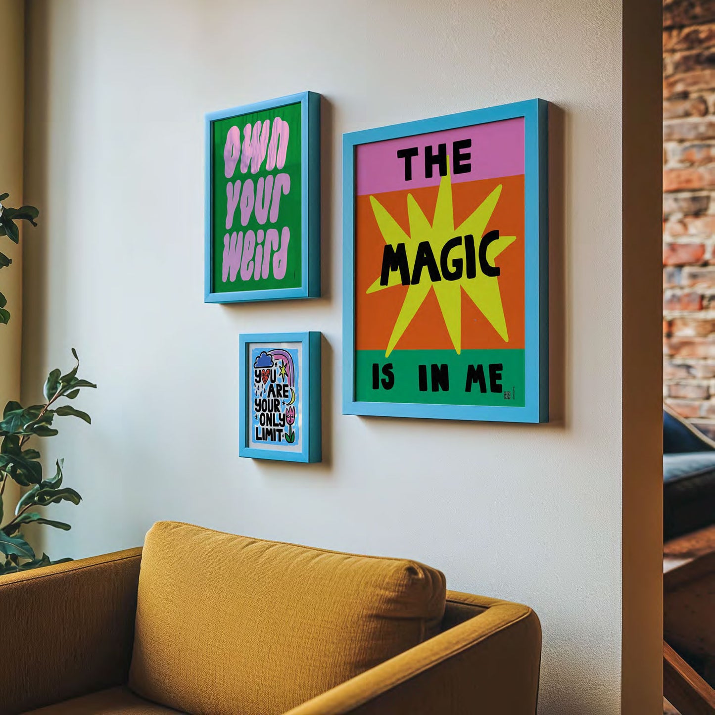 Colourful framed motivational artworks on a wall above a yellow couch.