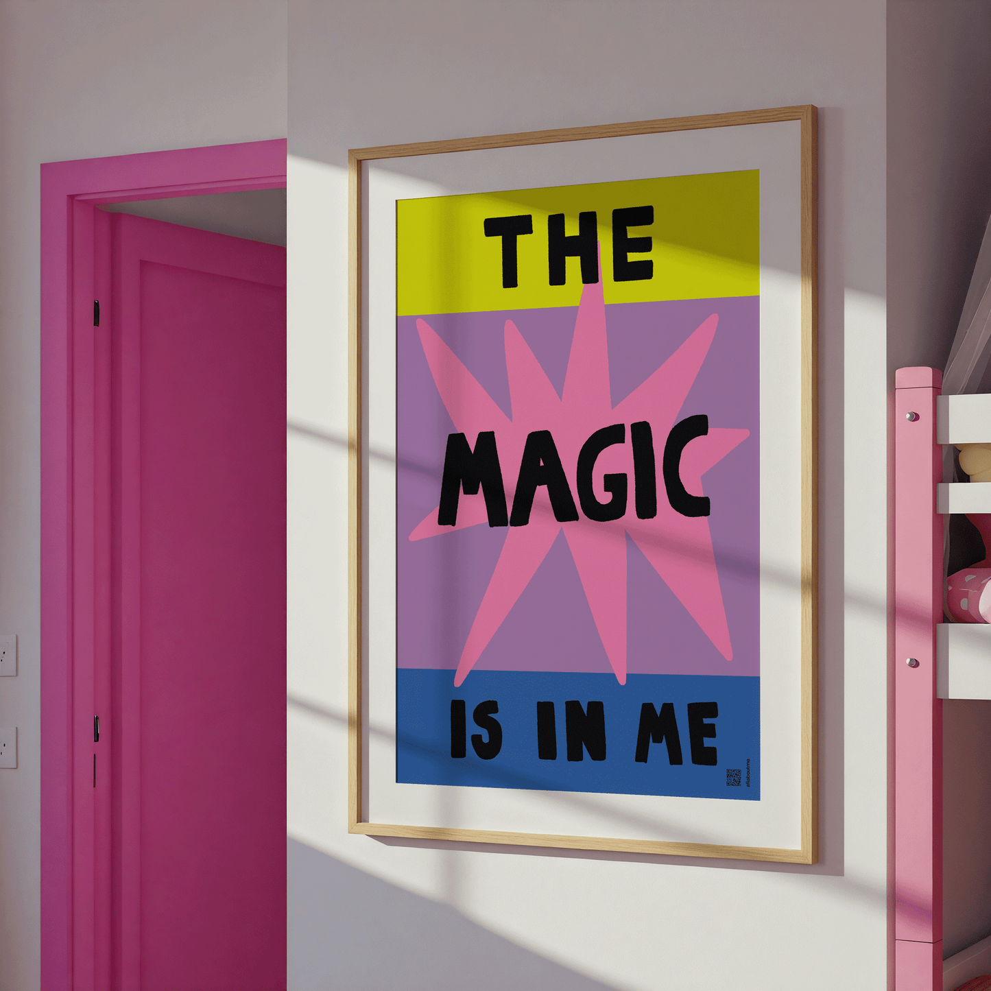 Framed poster with 'The Magic is in Me' text on a wall next to a pink door.