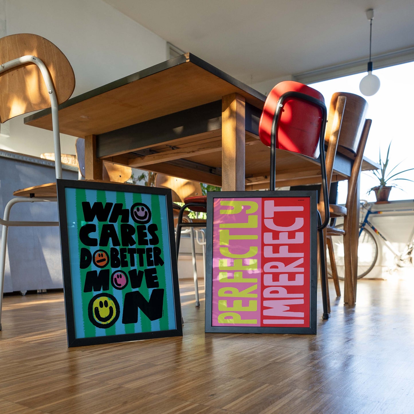 Two motivational posters on a wooden floor with chairs and tables in the background.