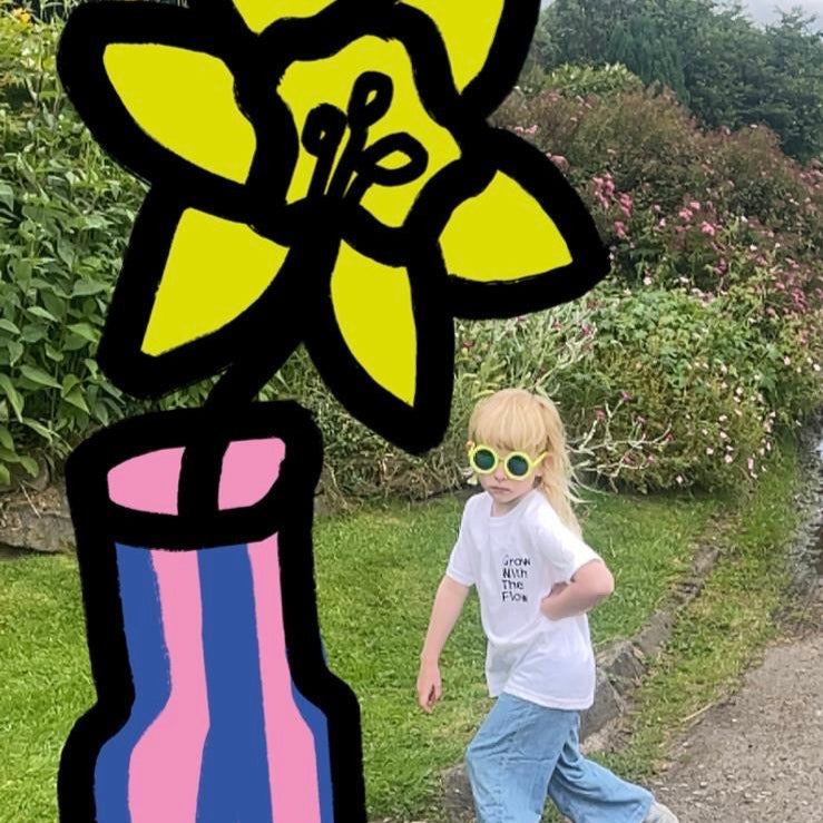 Child walking on a path with oversized augmented reality flowers superimposed over the image.